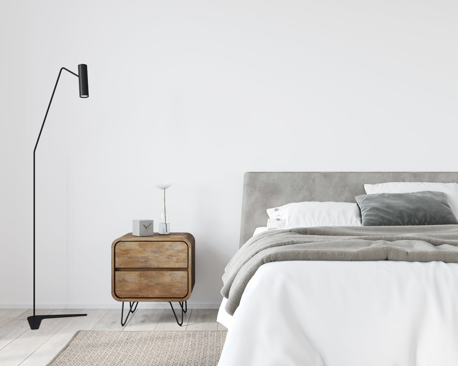 minimalist bedroom with grey bedding and small nightstand and standing light